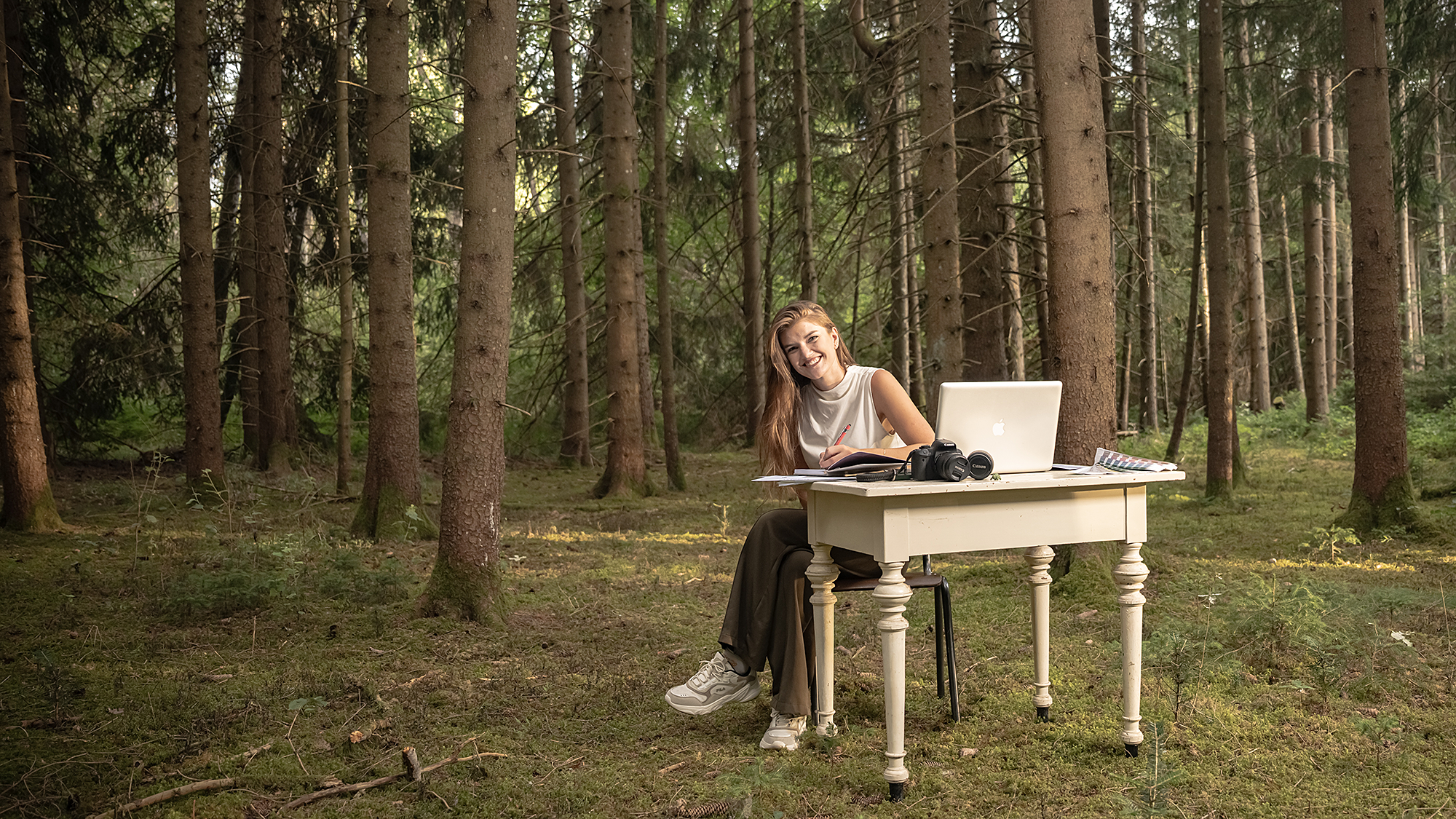 Nadine arbeitet an einem Schreibtisch mit Papier, Skizzen und Gestaltungsmaterialien